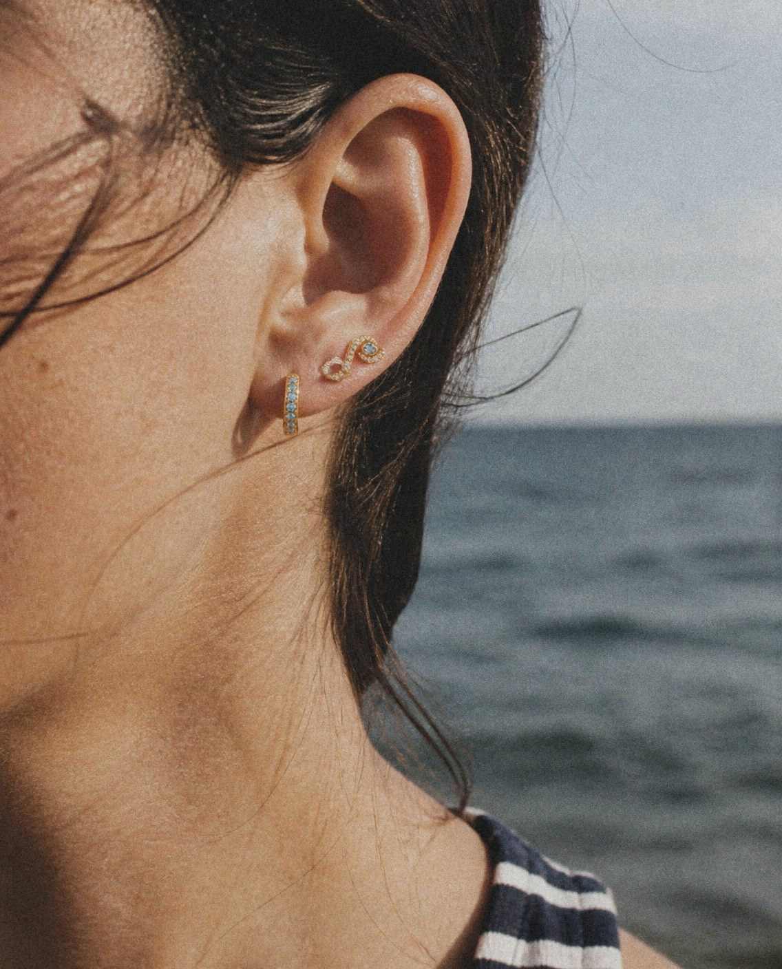 An Onda Stud and a Mare Pavé Huggie, worn by the sea